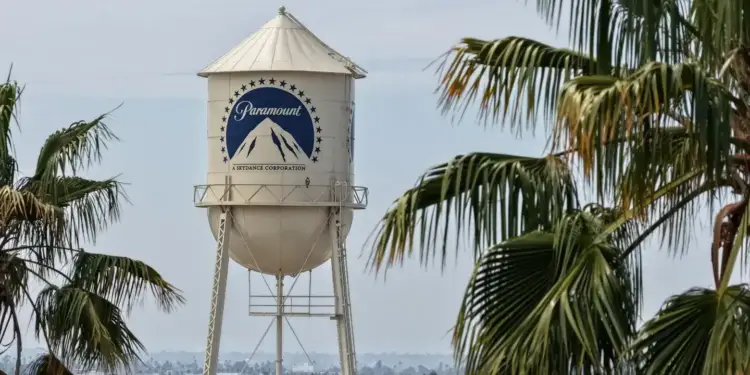 Torre de agua blanca con el logotipo azul de Paramount rodeada de palmeras en un entorno urbano.