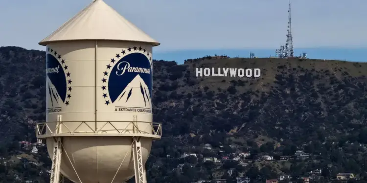 Torre de agua corporativa en primer plano con el cartel de Hollywood en una colina al fondo.