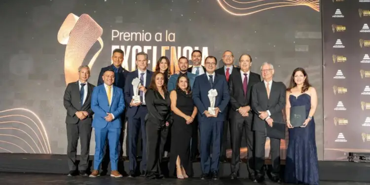 Grupo de profesionales recibiendo premios en un evento de gala, con un fondo que dice 'Premio a la Excelencia' y logos de 'Progreso'.