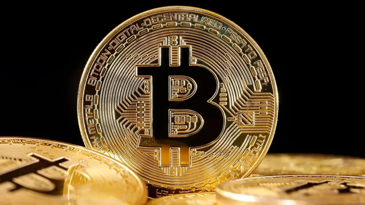 Primer plano de una moneda física dorada de Bitcoin con circuitos grabados sobre un fondo oscuro.