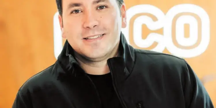 Retrato de medio cuerpo de un hombre de negocios sonriendo con chaqueta negra y texto n1co de fondo