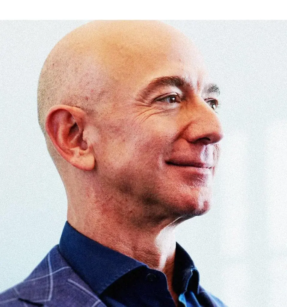 Primer plano de un hombre calvo, de perfil, sonriendo ligeramente, vestido con camisa azul y chaqueta a cuadros. Representa un profesional de negocios.