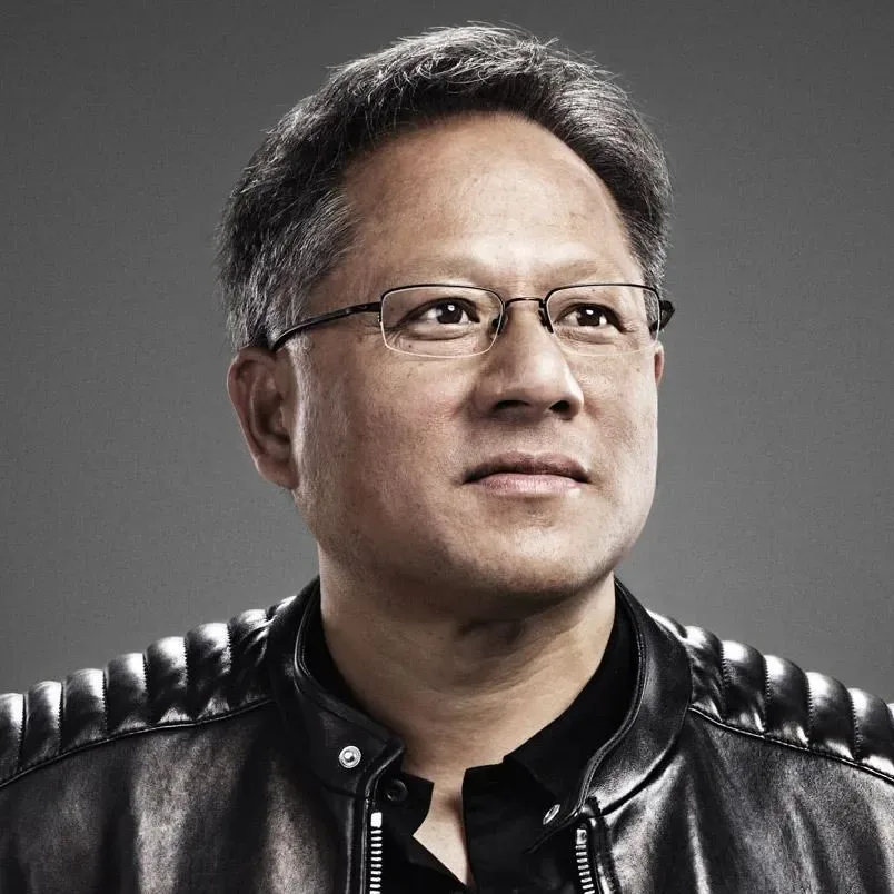Retrato de un hombre asiático de mediana edad con gafas y chaqueta de cuero negra, mirando pensativamente hacia arriba y a la derecha sobre un fondo gris.