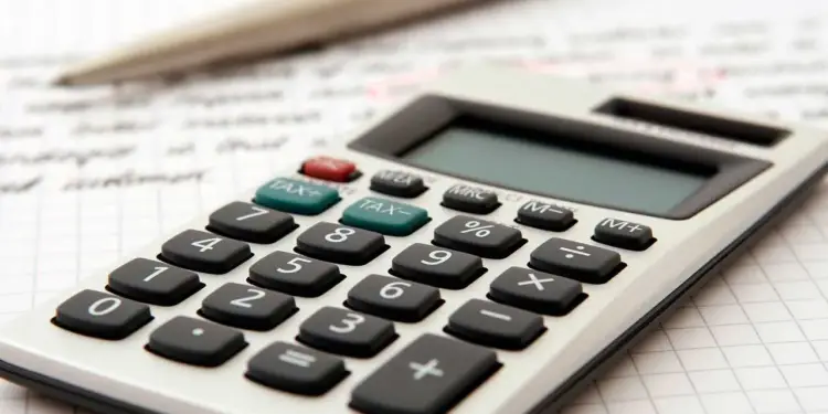 Calculadora de escritorio sobre papel cuadriculado con apuntes y un bolígrafo para cálculos financieros