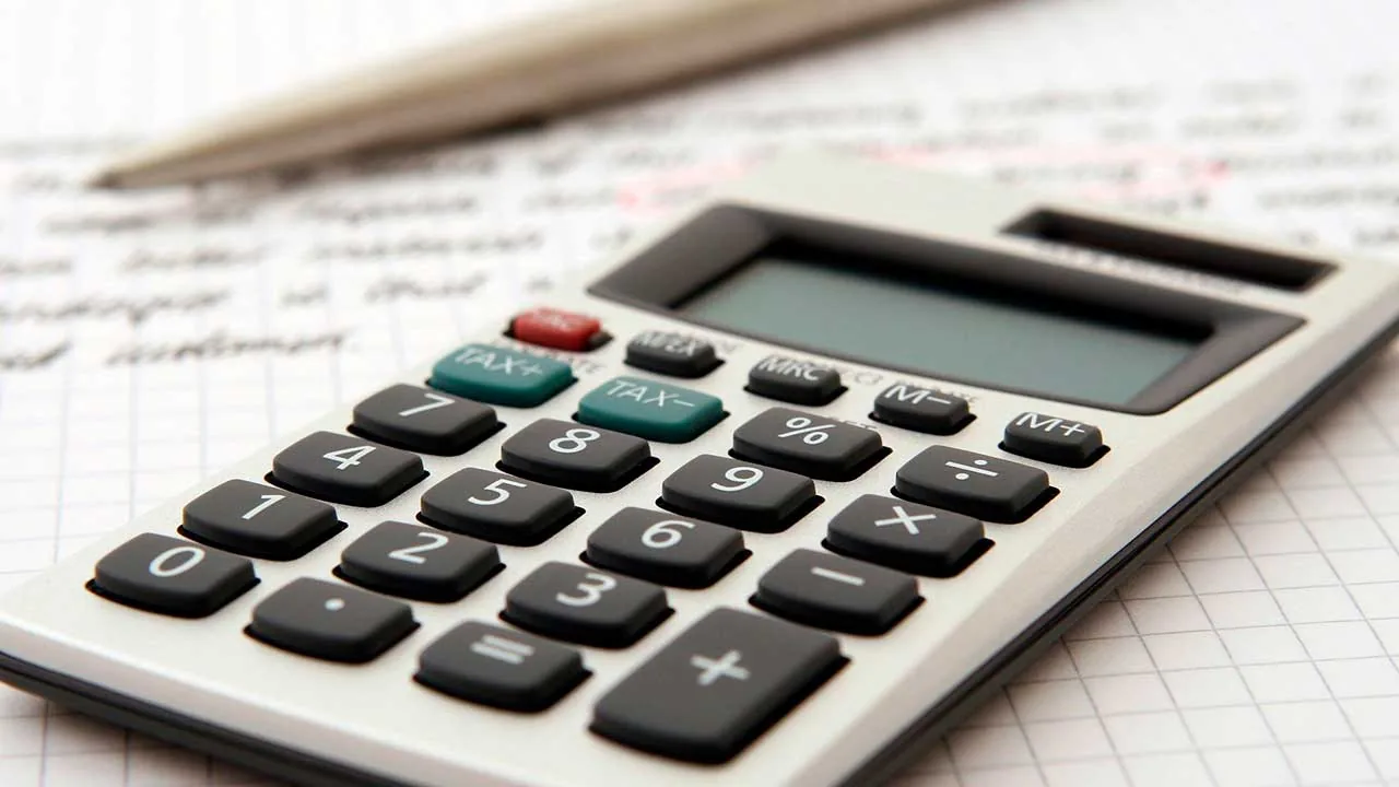 Calculadora de escritorio sobre papel cuadriculado con apuntes y un bolígrafo para cálculos financieros