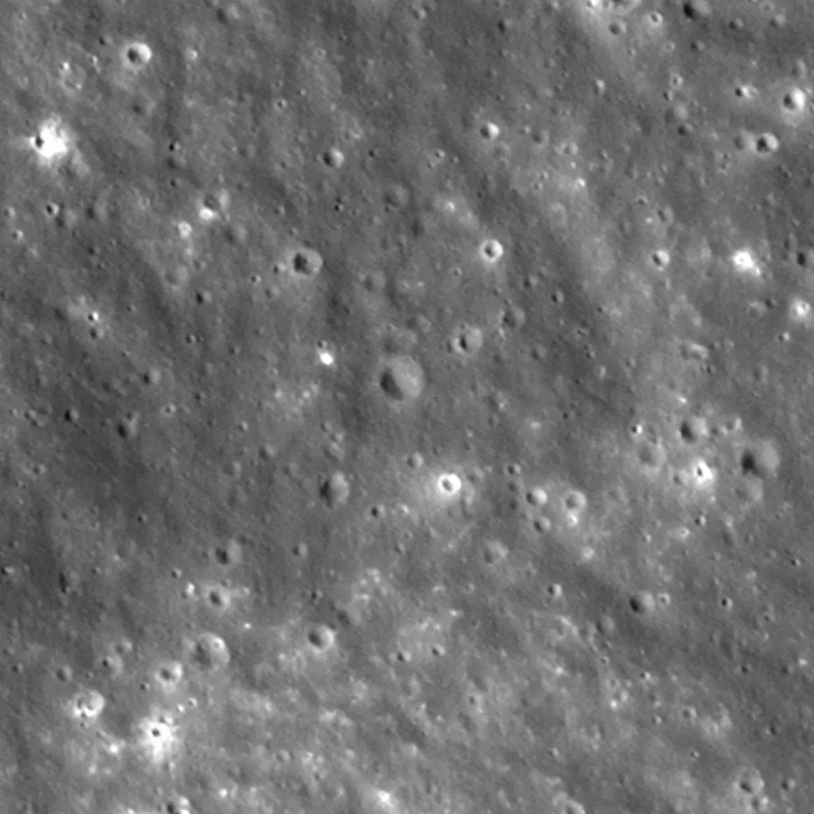 Imagen en escala de grises que muestra la superficie lunar llena de múltiples cráteres de impacto de diversos tamaños.