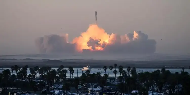 Un cohete espacial despega generando una enorme nube de fuego y humo al fondo, visto desde una zona costera con palmeras.