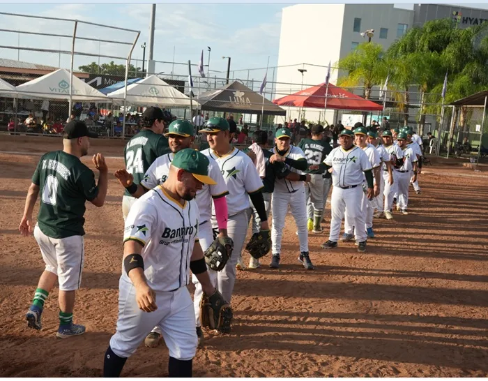Jugadores de béisbol con uniformes deportivos saludándose en fila sobre el terreno de juego.