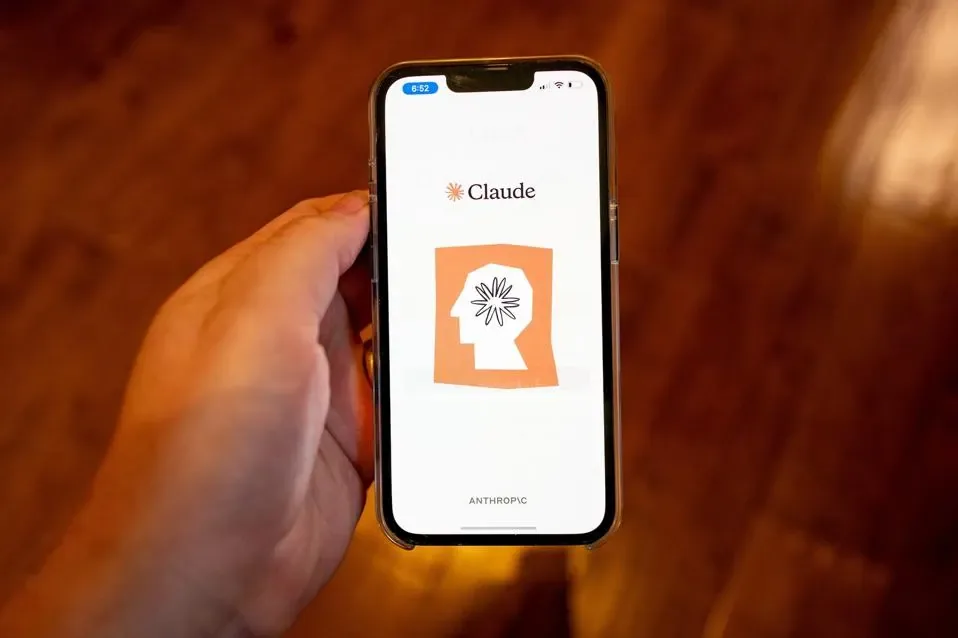 Mano sosteniendo un teléfono inteligente que muestra la aplicación Claude en la pantalla.