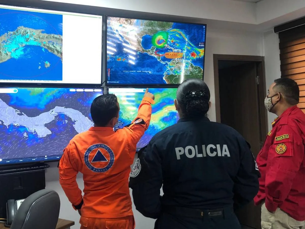 Personal de emergencia, policía y bomberos observando pantallas con mapas meteorológicos en un centro de control.