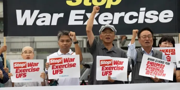Grupo de personas manifestándose con pancartas que dicen Stop War Exercise UFS