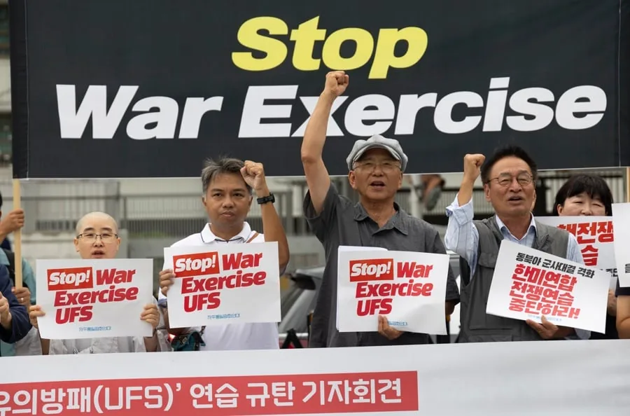 Grupo de personas manifestándose con pancartas que dicen Stop War Exercise UFS