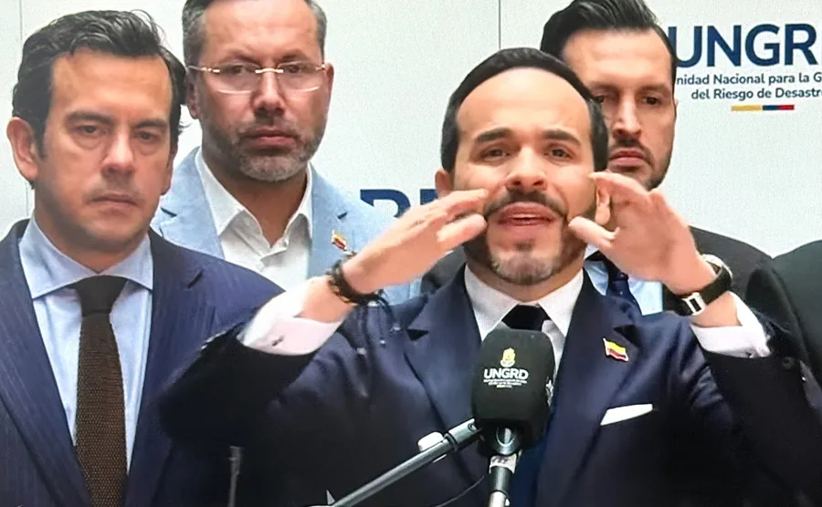 Cuatro hombres con traje y corbata en una conferencia de prensa frente a un micrófono.