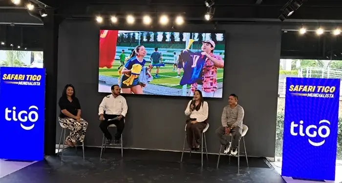 Cuatro personas en un panel de discusión frente a una pantalla LED que muestra una escena deportiva. A los lados, pantallas con el logo 'tigo' y 'Safari Tigo Mundialista'.