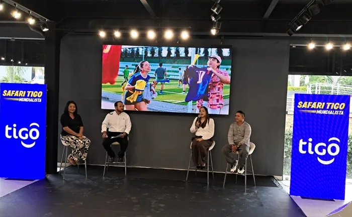 Cuatro personas en un panel de discusión frente a una pantalla LED que muestra una escena deportiva. A los lados, pantallas con el logo 'tigo' y 'Safari Tigo Mundialista'.