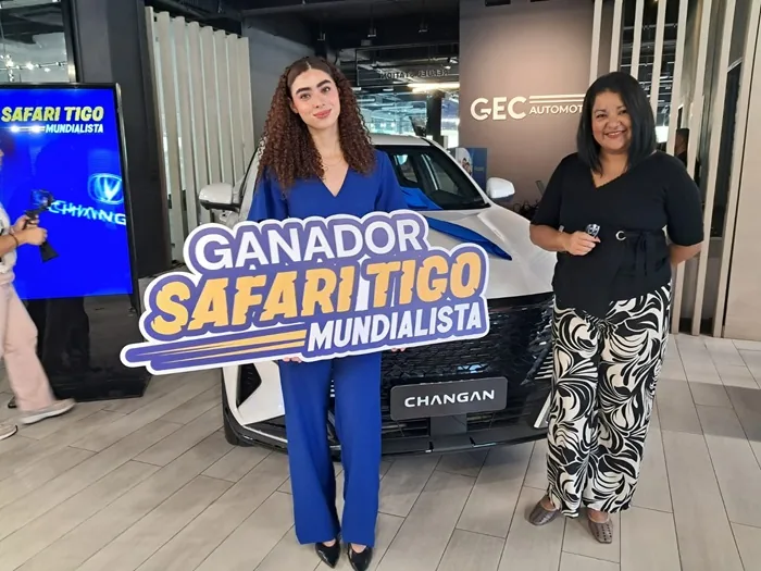 Dos mujeres sonríen frente a un automóvil blanco Changan con un lazo azul. Una sostiene un cartel de 'Ganador Safari Tigo Mundialista', la otra una llave.