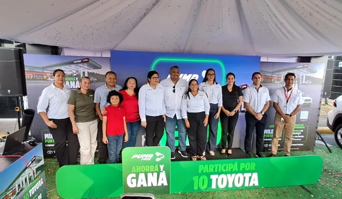Grupo de personas sonrientes posando en un evento corporativo frente a un panel publicitario con la leyenda Ahorrá y Ganá