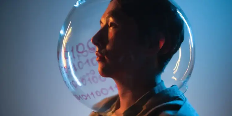 Perfil de una persona con un casco transparente que refleja números y código binario. Iluminación azul y naranja, simbolizando la era digital y los datos.