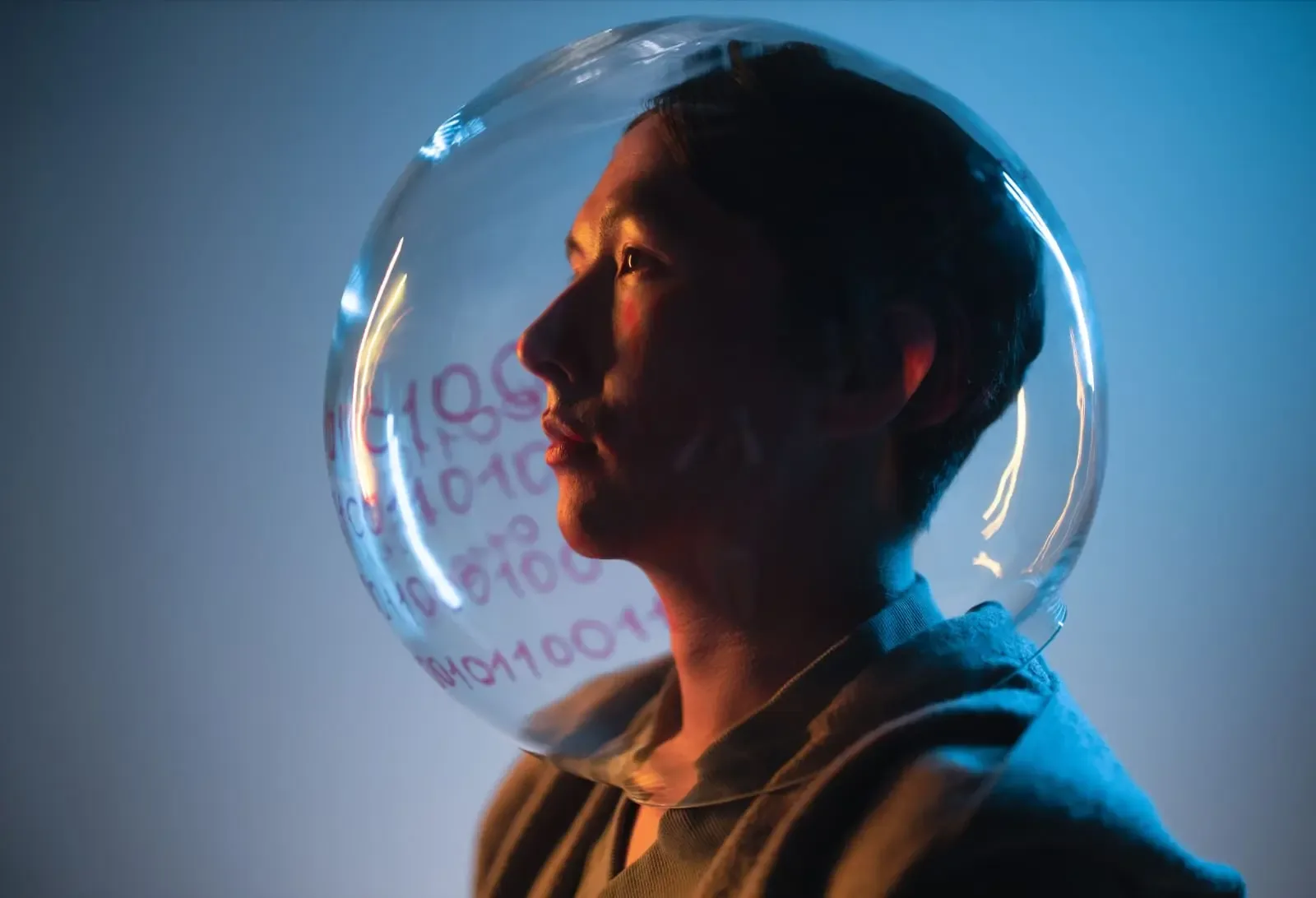 Perfil de una persona con un casco transparente que refleja números y código binario. Iluminación azul y naranja, simbolizando la era digital y los datos.