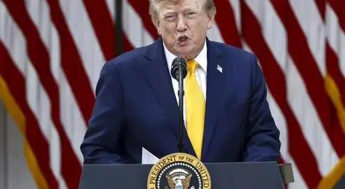 Donald Trump hablando frente a un atril con el sello presidencial y banderas de Estados Unidos al fondo.
