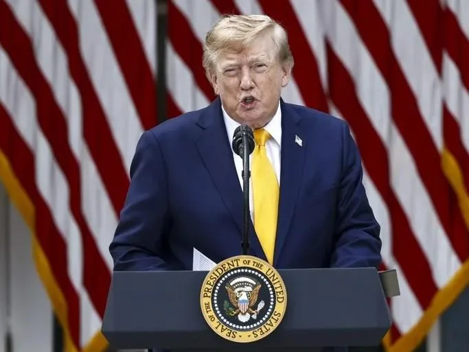 Donald Trump hablando frente a un atril con el sello presidencial y banderas de Estados Unidos al fondo.