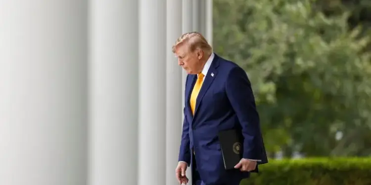 Hombre de negocios con traje azul oscuro y corbata amarilla caminando entre grandes columnas blancas.