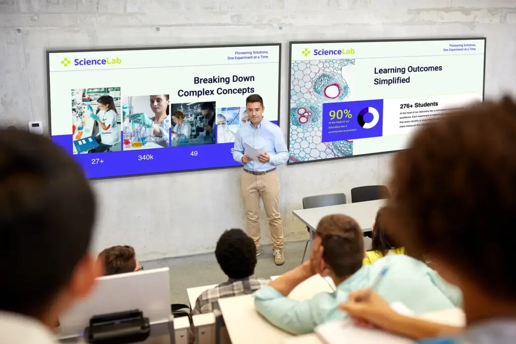 Hombre presenta en aula con dos pantallas mostrando datos de ciencia y educación a estudiantes. Ambiente de formación profesional.