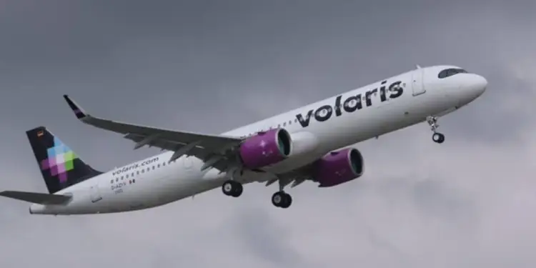 Avión de pasajeros blanco con motores morados y el logo 'Volaris' en el fuselaje, despegando bajo un cielo nublado.
