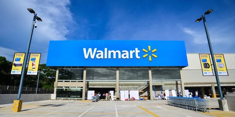 Vista frontal de una tienda Walmart bajo un cielo azul con estacionamiento vacío