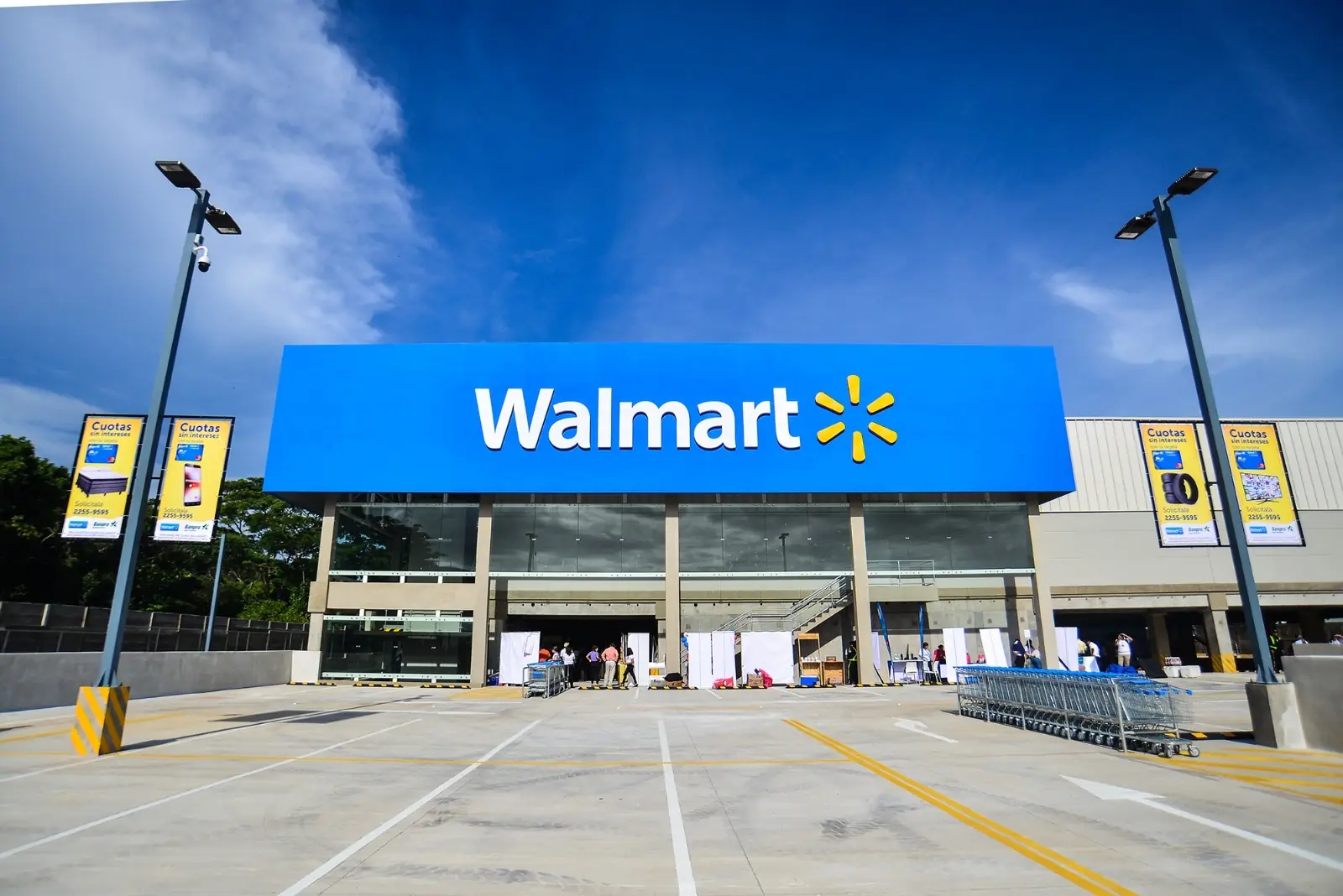 Vista frontal de una tienda Walmart bajo un cielo azul con estacionamiento vacío