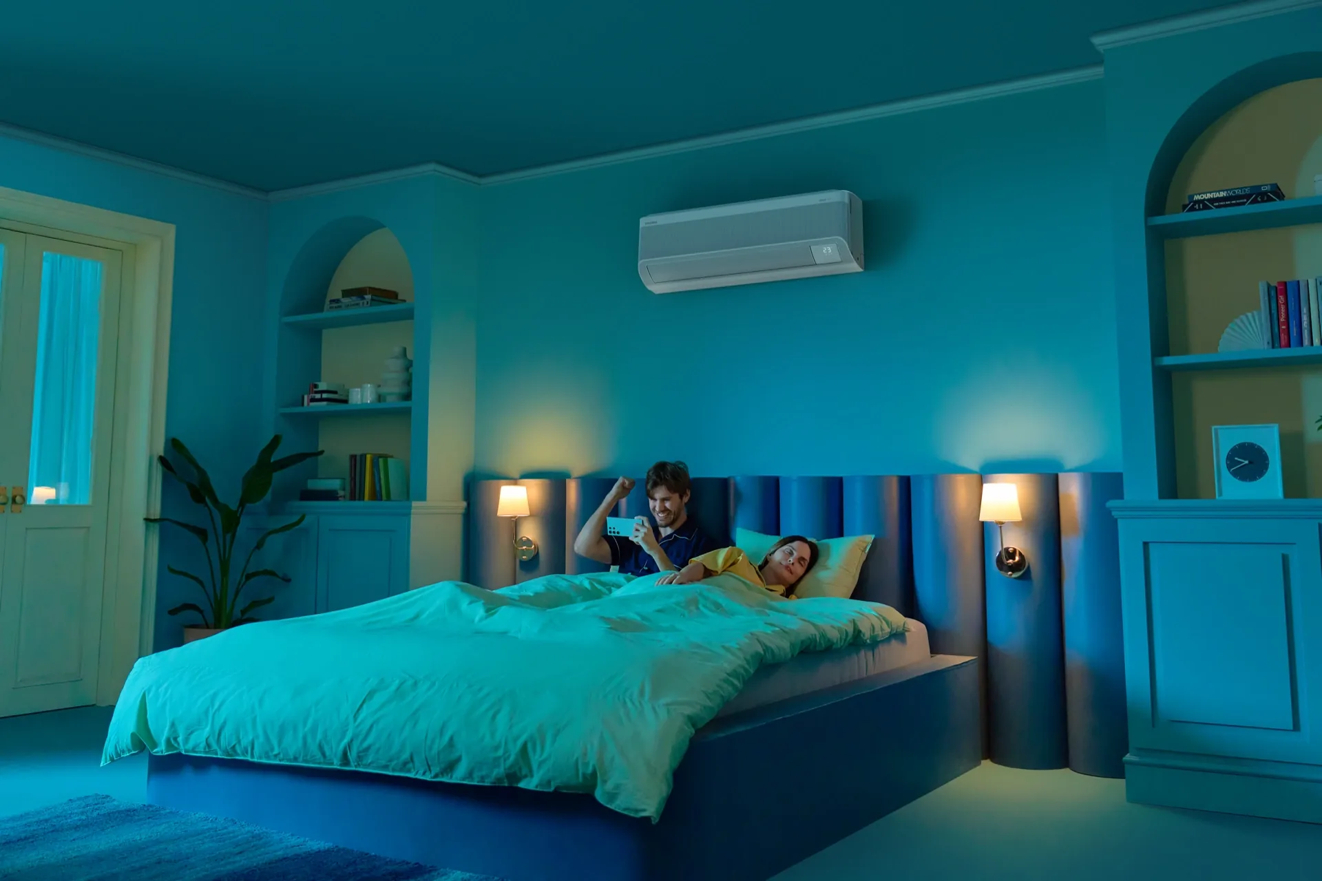 Pareja en una habitación iluminada de azul usando un teléfono móvil para controlar un aire acondicionado.