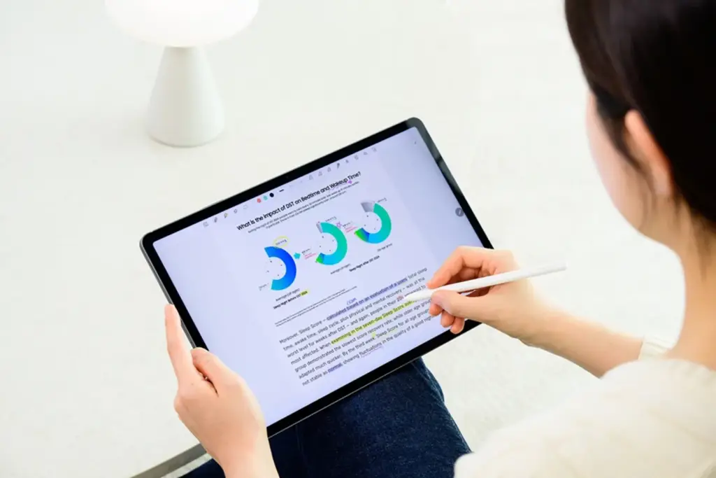 Persona revisando gráficos y documentos en una tablet digital con un lápiz óptico.