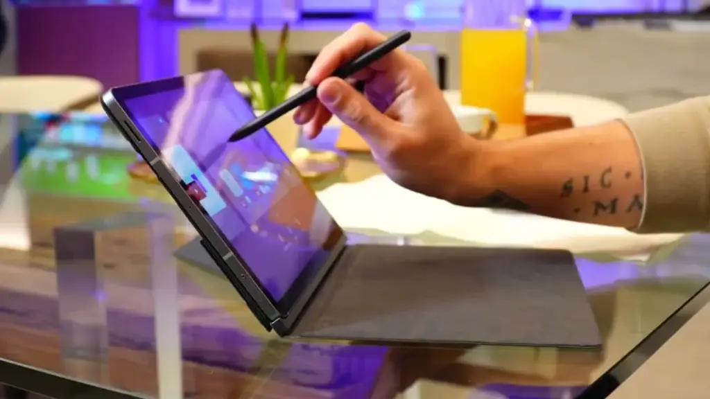 Persona utilizando un lápiz óptico sobre la pantalla táctil de una tableta colocada sobre una mesa de cristal.
