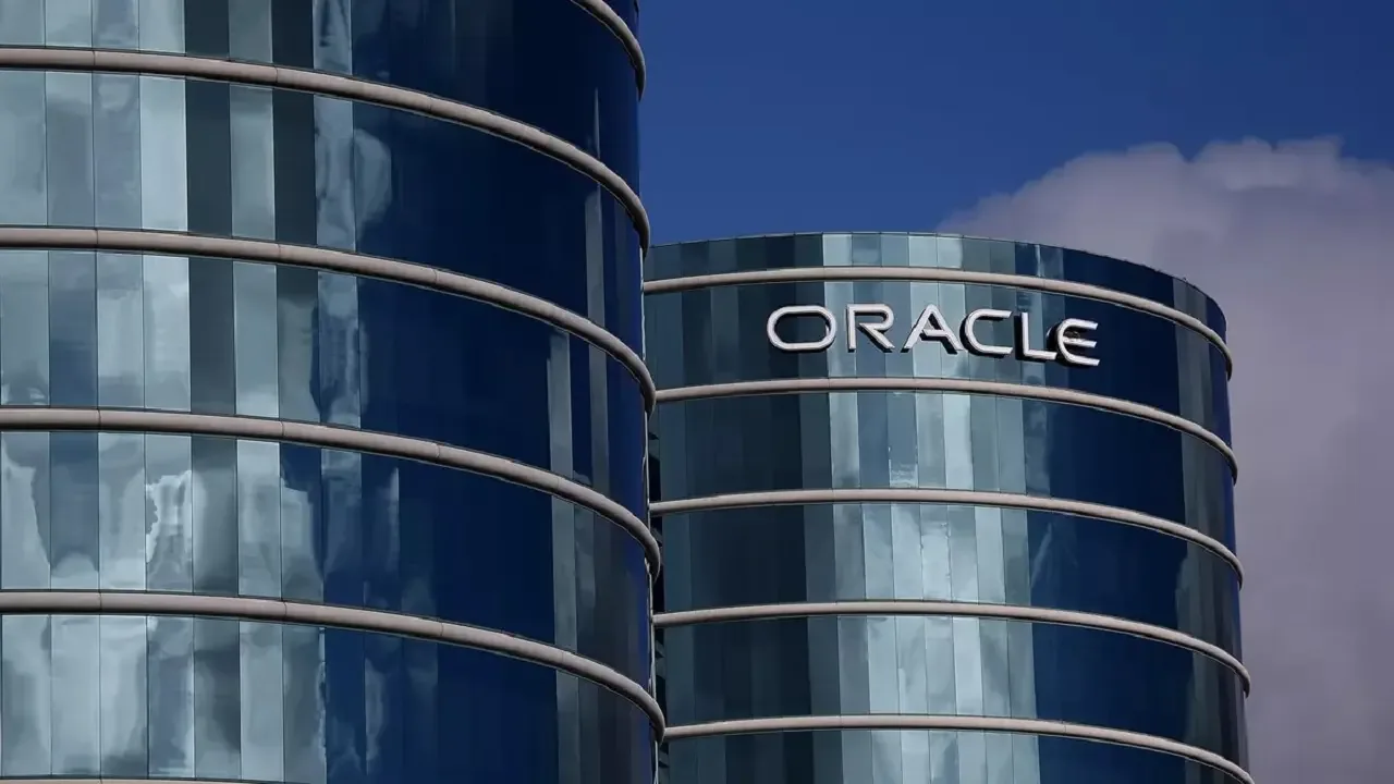 Fachada de vidrio de dos torres corporativas circulares con el letrero de Oracle bajo un cielo azul.