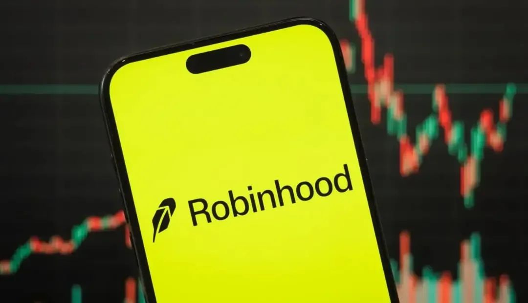 Primer plano de un smartphone con la aplicación Robinhood abierta en pantalla de color amarillo brillante, con un gráfico de velas de bolsa en segundo plano.