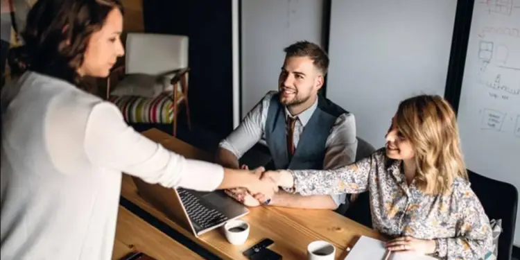Mujeres y hombre estrechando las manos en una reunión de negocios en la oficina