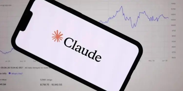 Un smartphone con el logo y nombre 'Claude' en pantalla, superpuesto sobre un monitor que muestra un gráfico de líneas financieras y datos de mercado.