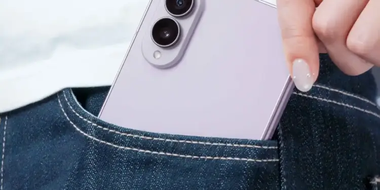 Mano de una persona guardando un smartphone violeta con doble cámara en el bolsillo trasero de unos jeans azules.