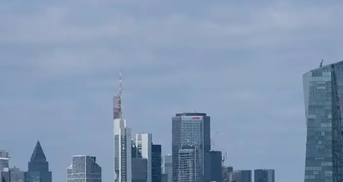 Vista panorámica de un horizonte urbano con rascacielos modernos, incluyendo uno con antena y otro de vidrio curvado, bajo cielo nublado.