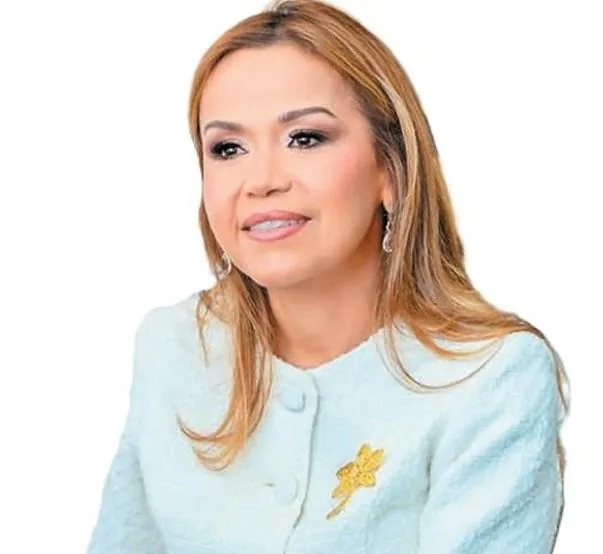 Retrato de una mujer profesional con chaqueta clara y broche dorado sobre fondo blanco