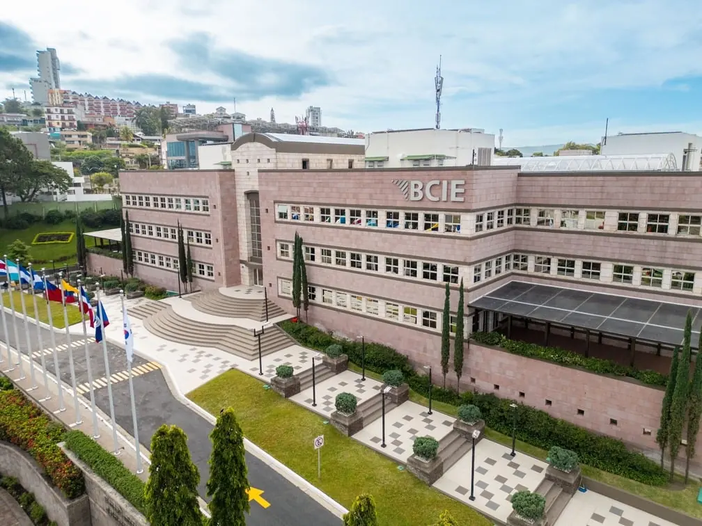 Vista exterior del moderno edificio corporativo del BCIE rodeado de áreas verdes y banderas