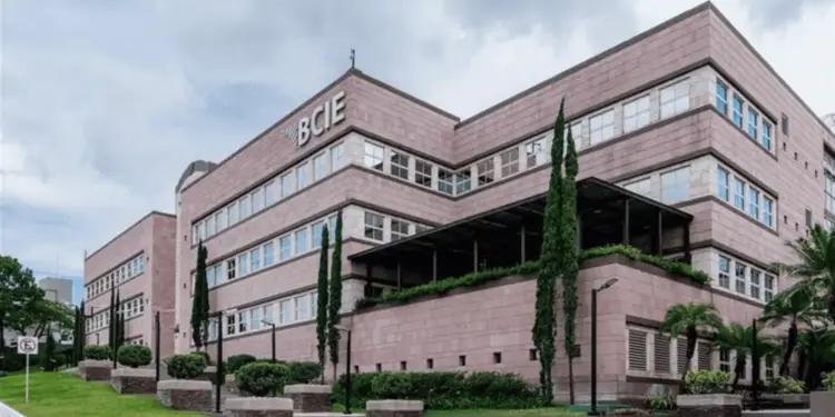 Vista exterior del moderno edificio institucional con fachada de piedra rosada y el logotipo de BCIE.