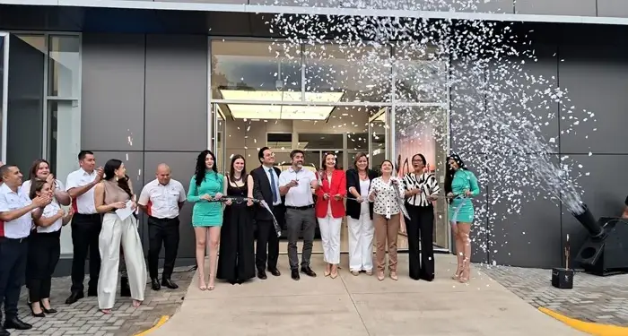 Grupo de personas cortando una cinta en la inauguración de un local con lluvia de papelillos.