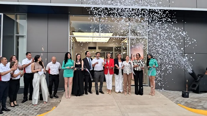 Grupo de personas cortando una cinta en la inauguración de un local con lluvia de papelillos.