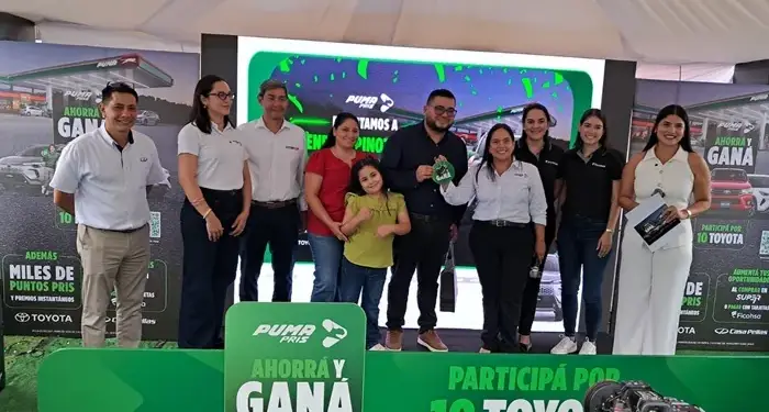 Grupo de personas sonrientes en un evento promocional con pantallas y pancartas corporativas