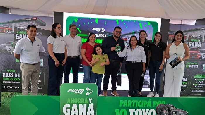 Grupo de personas sonrientes en un evento promocional con pantallas y pancartas corporativas