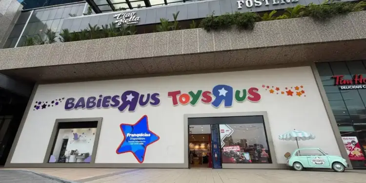 Fachada de un centro comercial con las tiendas Babies R Us y Toys R Us. Se observa un letrero de 'Franquicias Disponibles' y un coche decorativo.