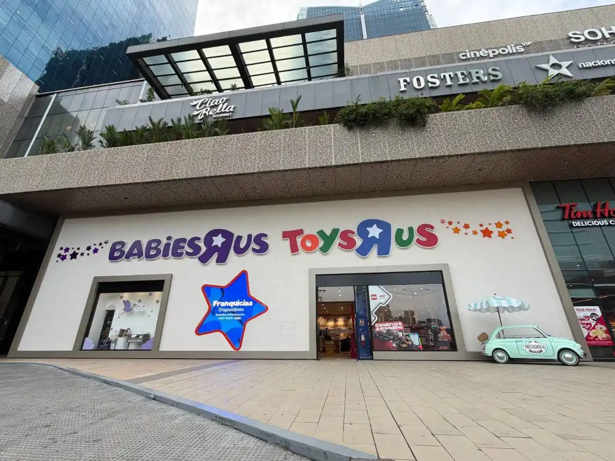 Fachada de un centro comercial con las tiendas Babies R Us y Toys R Us. Se observa un letrero de 'Franquicias Disponibles' y un coche decorativo.
