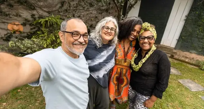 Cuatro amigos de diversas edades y etnias tomándose una autofoto sonrientes en un jardín.