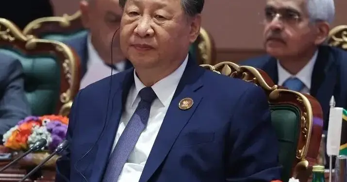 Xi Jinping en una mesa de conferencia luciendo traje azul marino y audífono durante una cumbre.